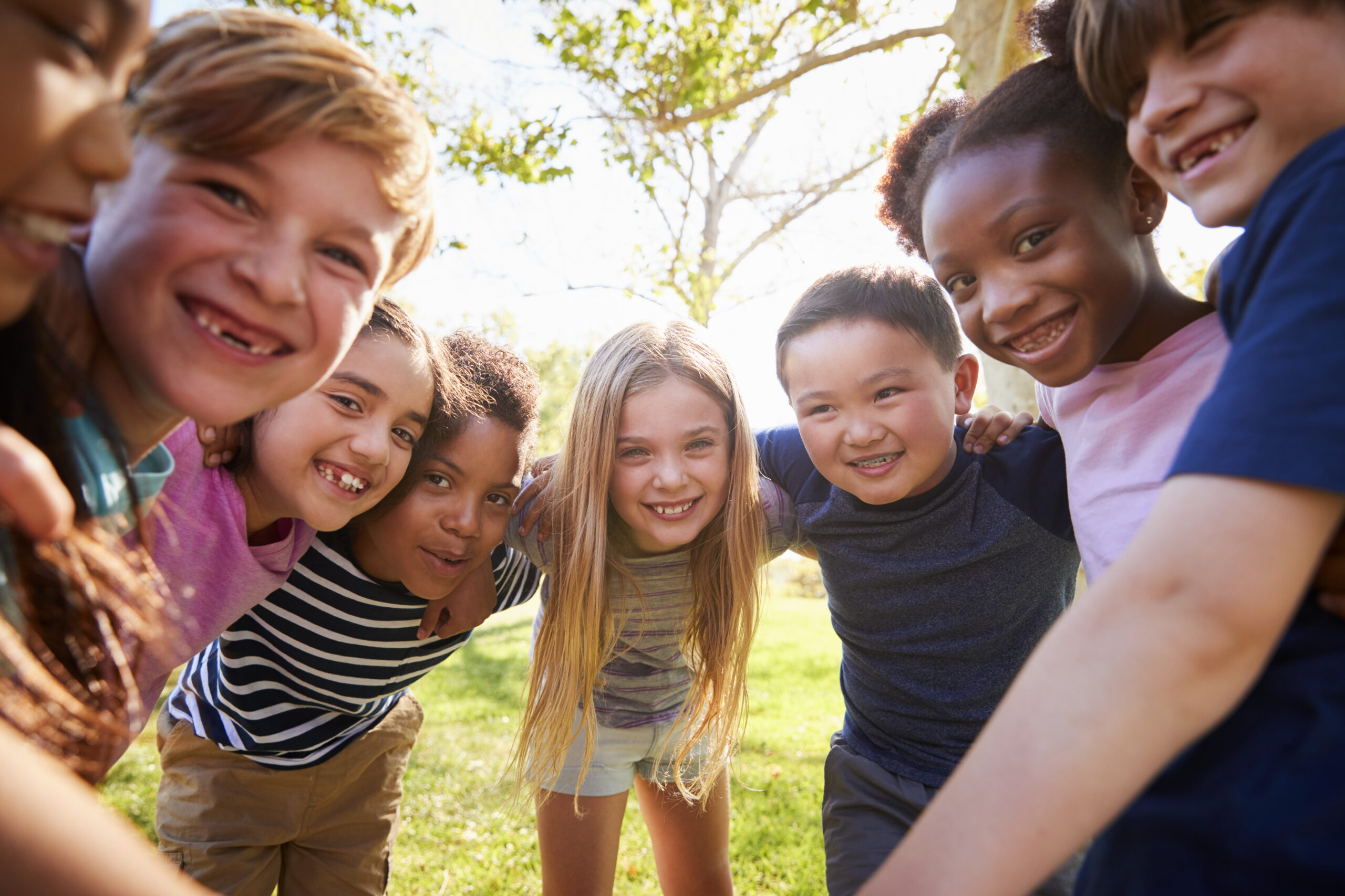 Smiling schoolchildren leaning into the camera together at kids club