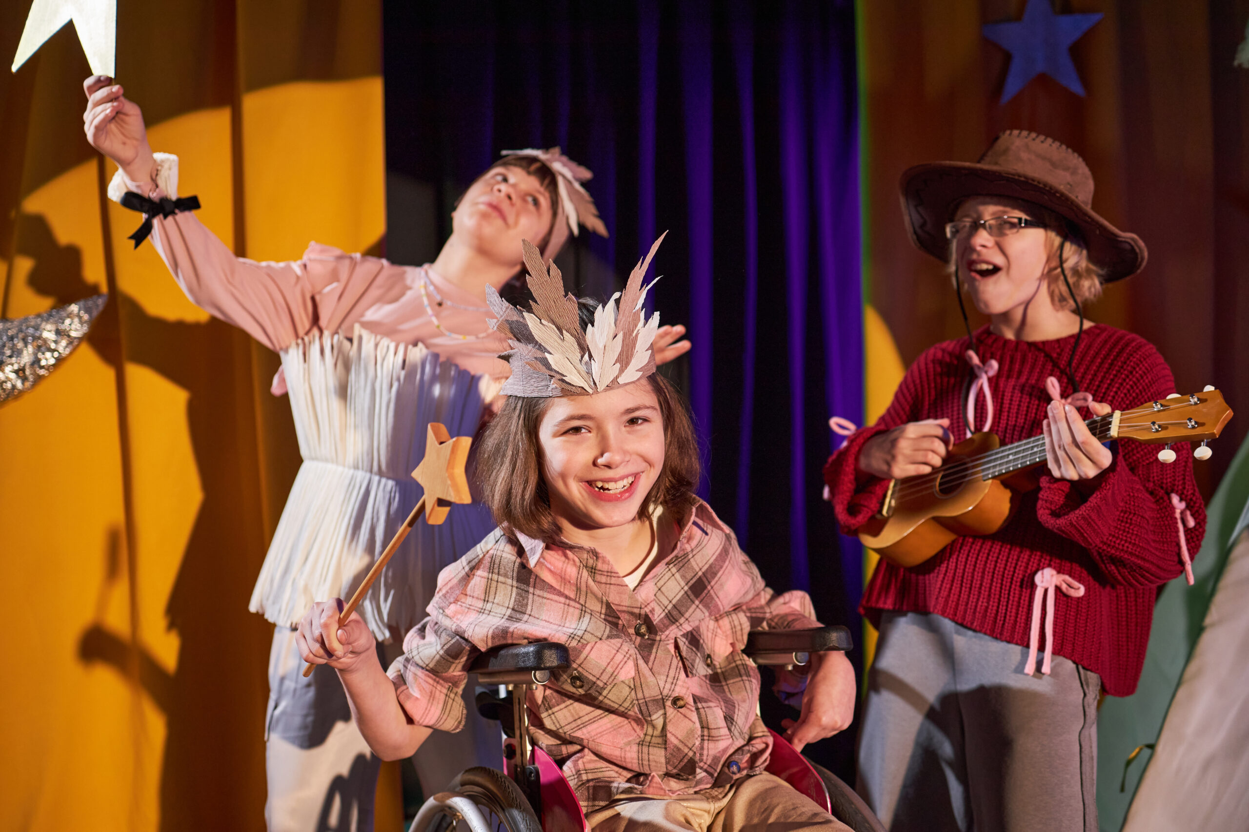 Happy young girl in wheelchair performing on stage during an inclusive drama activity
