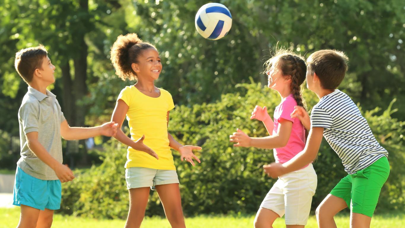Children smiling and playing ball outdoors at Horizon Kids Club in Berkhamsted