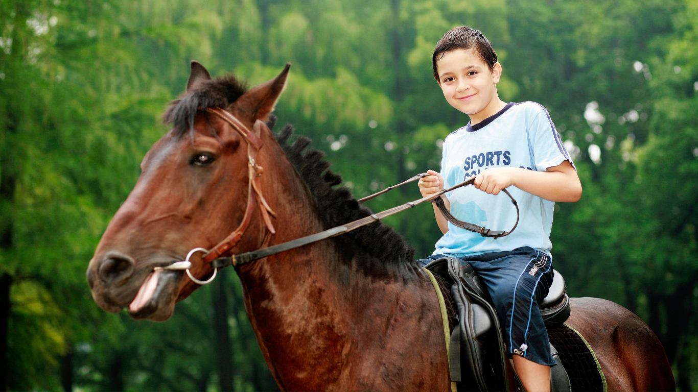 Boy riding a horse during an outdoor holiday club activity
