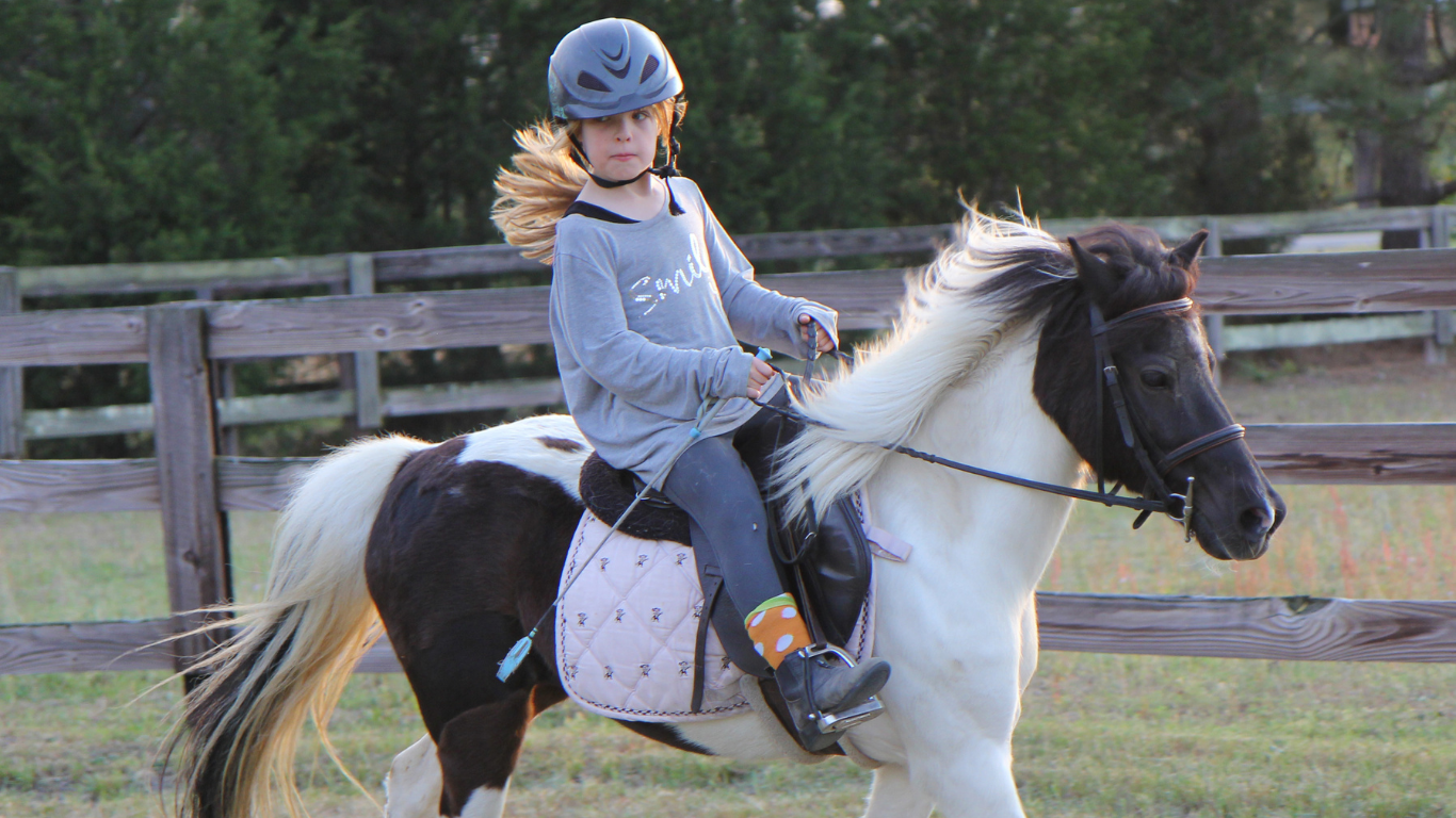 Girl pony riding in a field during an outdoor holiday club activity